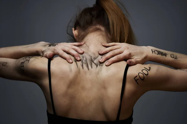 Vrouw met beledigende inscripties op haar lichaam aanraken van zichzelf met handen stress frustratie haat — Stockfoto