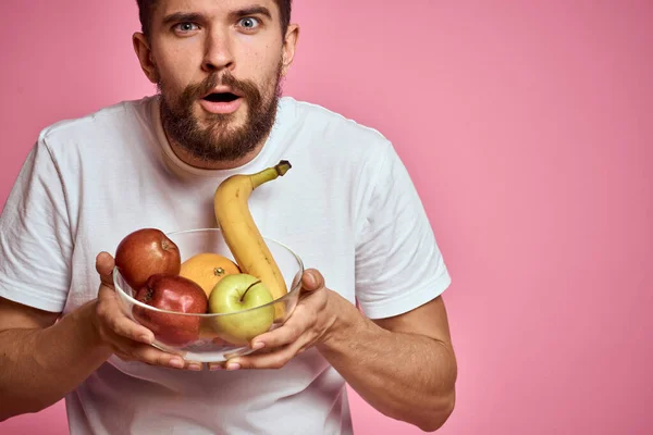 Hombre enérgico con fruta fresca en una taza sobre un espacio de copia de fondo rosa — Foto de Stock