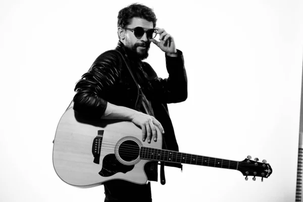 男が黒い革のジャケットでギターを弾き、サングラスをかけている。 — ストック写真