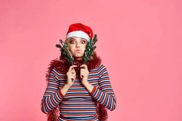 Žena s vánoční strom větve v rukou červená tinsel a slavnostní klobouk růžové pozadí oříznutý pohled — Stock fotografie