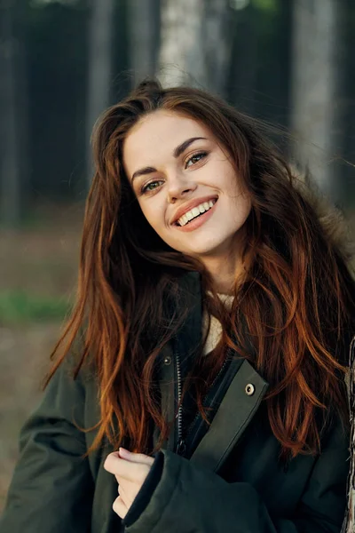 Mujer sonriente en chaqueta al aire libre en el viaje por el bosque —  Fotos de Stock