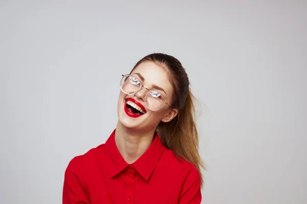 Donna alla moda in una camicia rossa su uno sfondo leggero emozioni divertenti occhiali trucco luminoso aspetto attraente — Foto Stock
