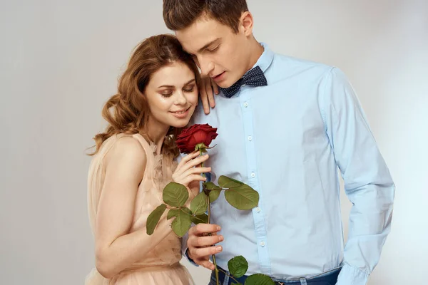 Ein liebendes junges Paar mit einer roten Rose in der Hand auf hellem Hintergrund — Stockfoto