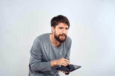 Elinde tablet olan sakallı bir adam. Gri ceketli, teknolojili, internet ışıklı bir arka plan.