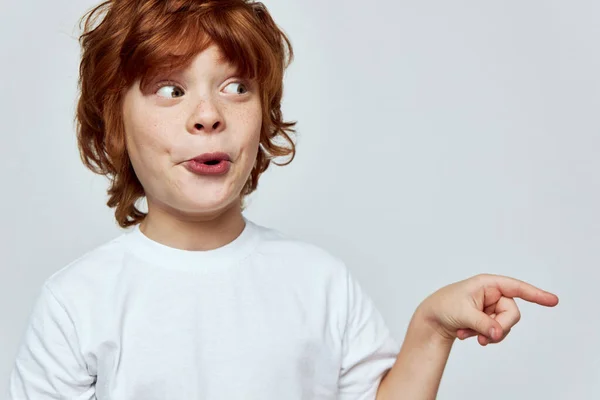 Überraschter Junge blickt zur Seite und zeigt fingergrauen Hintergrund. — Stockfoto