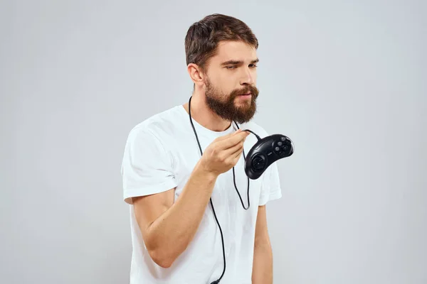 Een man met een gamepad in zijn handen spelen spelletjes vrije tijd lifestyle technologie wit t-shirt lichte achtergrond — Stockfoto