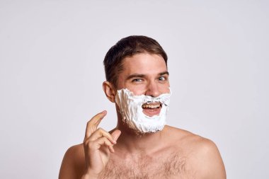 Yüzünde beyaz tıraş köpüğü olan yakışıklı bir adam ve jilet gibi omuzları olan temiz bir cilt.