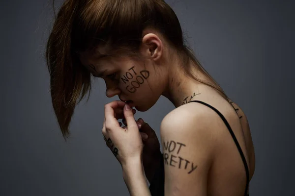 Emotionale Frau mit Inschriften auf Körper verärgert über Frustration grauen Hintergrund — Stockfoto