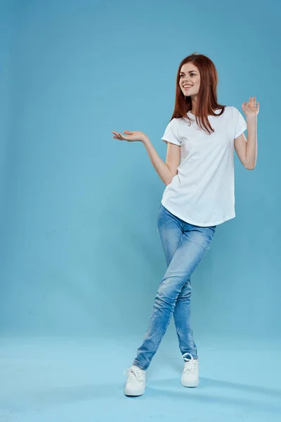 Mulher bonita em branco t-shirt azul jeans estilo de vida em pleno crescimento estúdio azul fundo — Fotografia de Stock