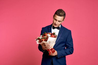 Çiçek buketi ve pembe arka planda papyonlu romantik bir adam.