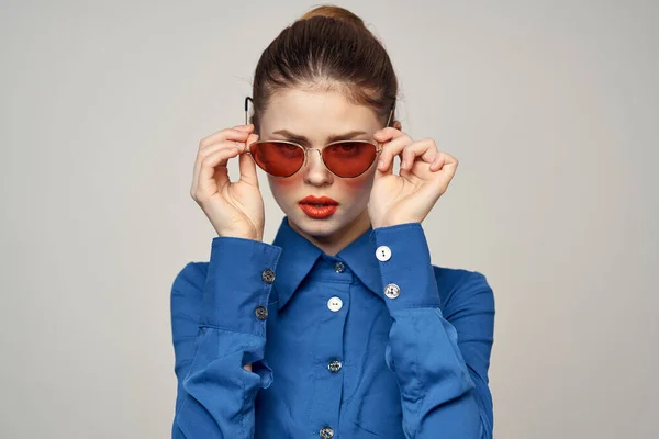 Güneş gözlüklü modaya uygun bir kadın ve elleri açık arka planda beliren mavi bir gömlek. — Stok fotoğraf