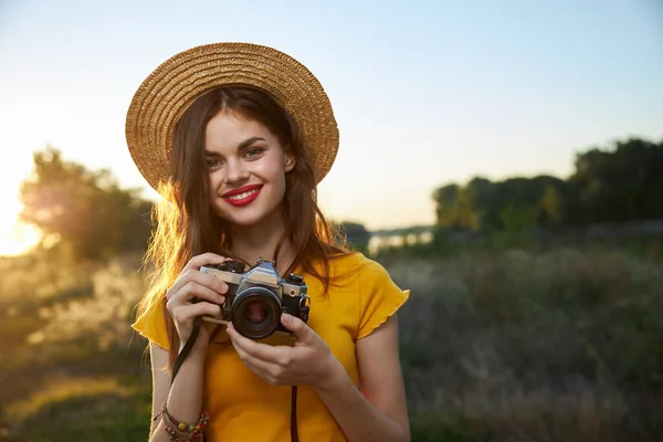 Kvinna fotograf kamera i händerna leende röda läppar hatt attraktiv look natur — Stockfoto