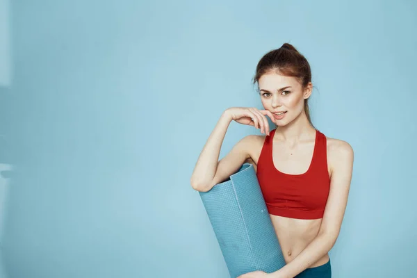 Donna sportiva in rosso serbatoio top mat per esercizi di allenamento stile di vita sfondo blu — Foto Stock