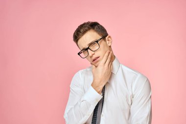 Beyaz gömlekli, kravatlı, gözlüklü, kendine güvenen, resmi pembe arka planlı bir iş adamı.
