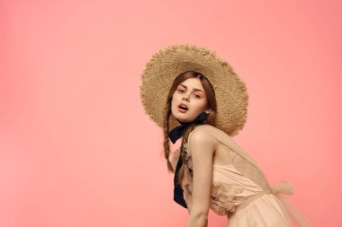 Şapkalı ve siyah kurdeleli güzel bir kadın. Pembe arka plan modeli.