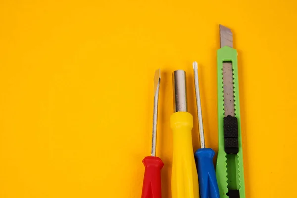 Chaves de fenda de faca de papelaria e ferramentas de construção em equipamentos de fundo amarelo para a indústria de reparação — Fotografia de Stock