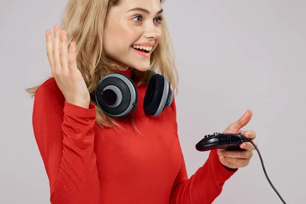 コンソールゲーム楽しいレジャー赤いジャケットライフスタイルの光の背景を手にヘッドフォンコントローラーを持つ女性 — ストック写真