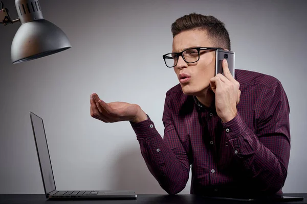 Homem de negócios em óculos e uma camisa senta-se a uma mesa com laptops abertos Coffee Space telefone móvel — Fotografia de Stock