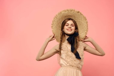 Şapkalı ve siyah kurdeleli güzel bir kadın. Pembe arka plan modeli.