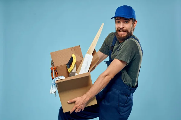 Trabalhador homem em caixa uniforme ferramentas construção azul fundo — Fotografia de Stock