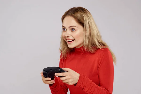 Mujer con mando en las manos jugando juegos emociones estilo de vida ocio camisa roja fondo claro — Foto de Stock