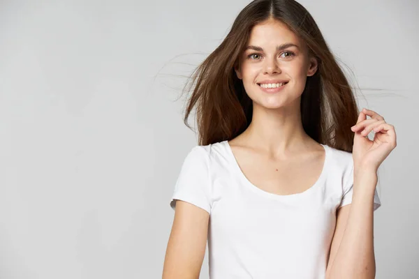 A happy woman in a white T-shirt on a light background smiling — Stock Photo, Image