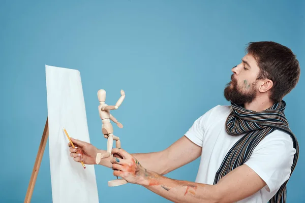 Männlicher Künstler mit einer Holzattrappe in den Händen Zeichnung Kreatives Hobby blauer Hintergrund — Stockfoto