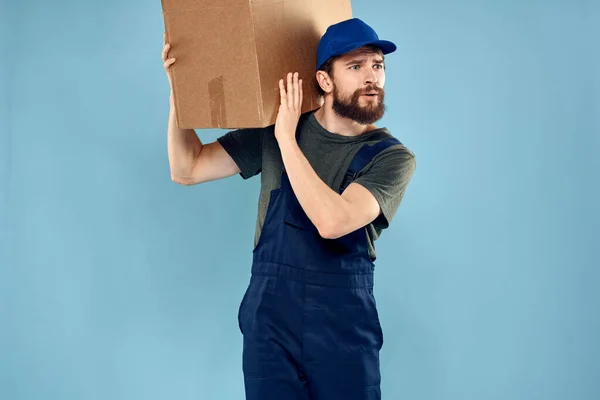 キャリッジデリバリサービスの青い背景の手に箱で制服を着た男 — ストック写真