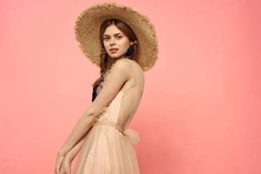 Şapkalı ve siyah kurdeleli güzel bir kadın. Pembe arka plan modeli.