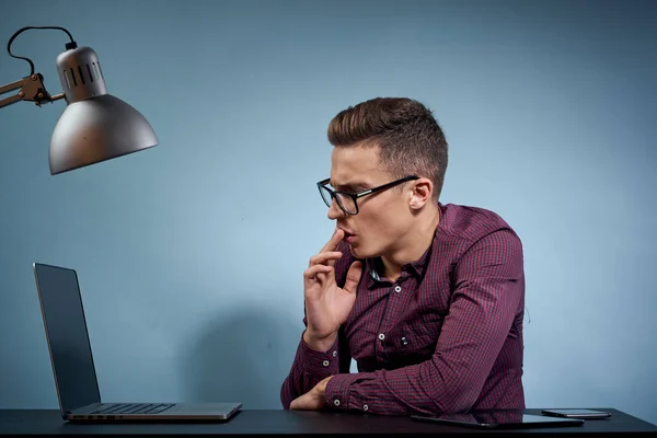Mężczyzna w koszuli z laptopem przy stole jest menadżerem w biurze i modelem szafki na lampy. — Zdjęcie stockowe