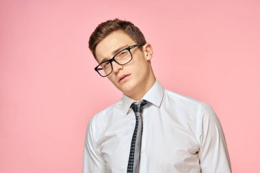 Beyaz gömlekli, kravatlı, gözlüklü, kendine güvenen, resmi pembe arka planlı bir iş adamı.