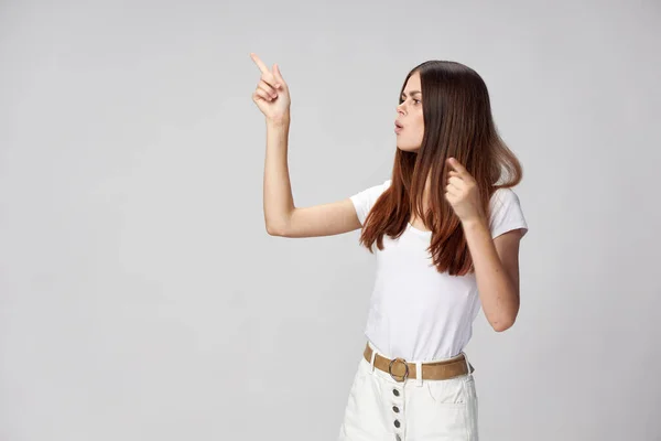 Una mujer interesada en una camiseta blanca señala sus pulgares hacia arriba — Foto de Stock