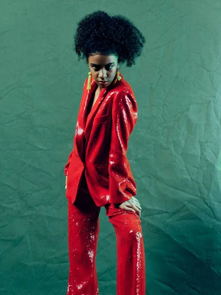 Vrouw in een rood glanzend pak versieren krullend donker haar luxe — Stockfoto