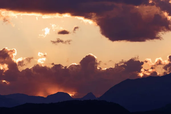 Sun peaks out from behind the clouds over Crowsnest Mountain and Seven Sisters Mountain