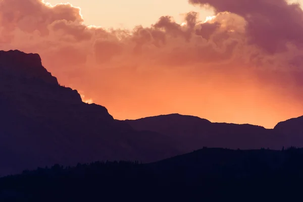 Sun peaks out from behind the clouds over Crowsnest Mountain and Seven Sisters Mountain