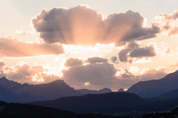 Sun peaks out from behind the clouds over Crowsnest Mountain and Seven Sisters Mountain