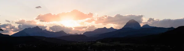 Sun peaks out from behind the clouds over Crowsnest Mountain and Seven Sisters Mountain