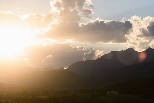 Sun peaks out from behind the clouds over Crowsnest Mountain and Seven Sisters Mountain