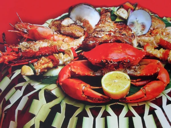 Deniz lezzetleri yemek için iyi seçim. Bir ıstakoz, yengeç bir limon, büyük karides ve midye bir tabak üzerinde.