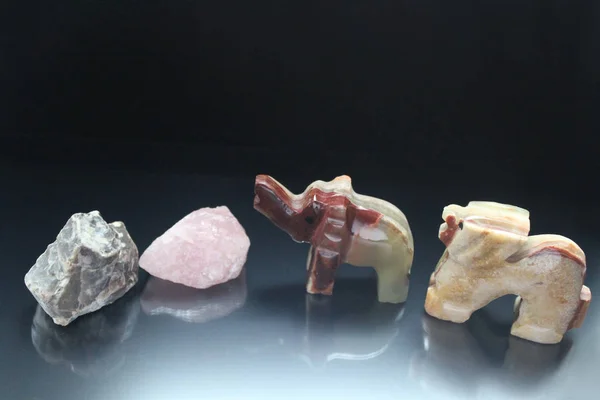 Gri ve pembe değerli maden taşlar ve fil buzağı ve bir kaplan bir taş gölge yansıması ile siyah bir zemin üzerine yapılmış güzel küçük hayvan. Yatay fotoğraf.