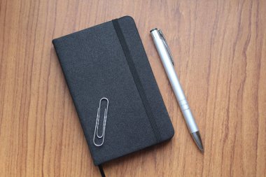 Siyah defter kayıtları, bir office ataş ve topu kalemin gümüş rengi bir tablo için. İş konu. Web tasarımında kullanılır.