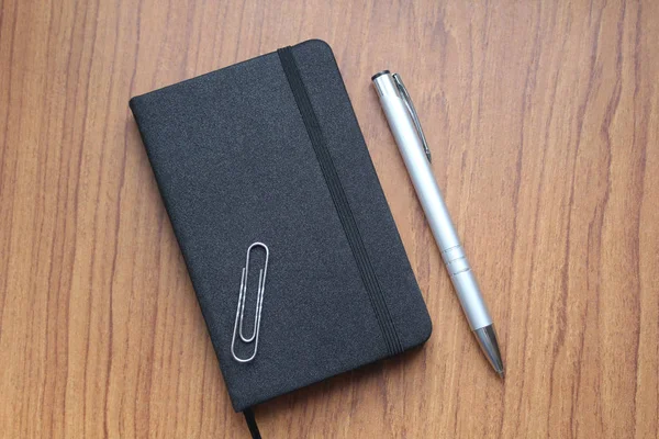 Siyah defter kayıtları, bir office ataş ve topu kalemin gümüş rengi bir tablo için. İş konu. Web tasarımında kullanılır.