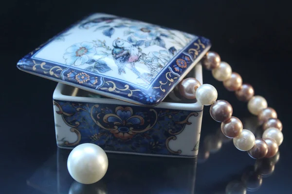 Seramik bir tabut, bir büyük boncuk yakın dan aşağı sarkan inci güzel boncuk. Takı siyah bir arka plan bir gölge ile. Kadınlar için takı. Kullanım için bir web tasarım.