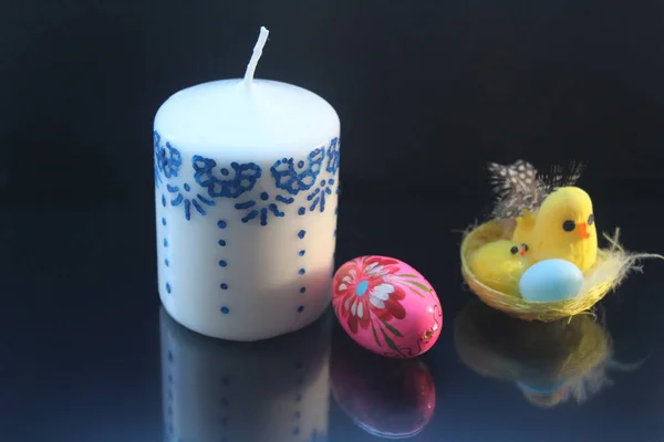 Makale sarı el yapımı tavuk ve civciv de Paskalya için mum kalıpları ve renkli bir pembe küçük yumurta bir tablo ile bir yuvaya. Gölge nesneleri siyah bir arka plan yansıtır. Mutlu Paskalya