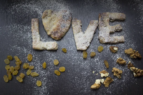 Ev yapımı hamur işleri kuru üzüm ve un ile koyu ahşap bir masa üzerinde ceviz ile lezzetli Kurabiye. Aşk testi gelen mektuplar. Ana sayfa görünümü, web tasarım, menü, takvimler için kullanılabilir.