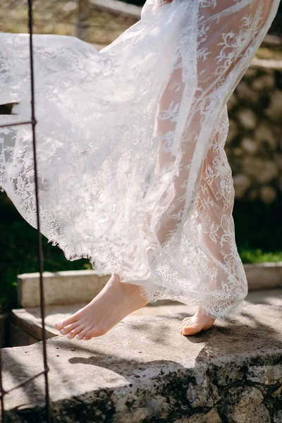 Low section view of woman in lace negligee walking on stone path