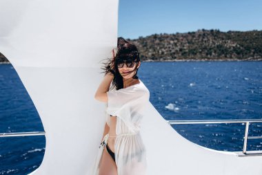 Kadın siyah bikini yat deniz arka plan üzerinde ayakta poz