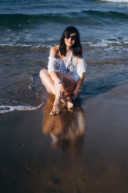 Güneş gözlüğü ve bikini Islak sahil üzerinde oturan kadın portresi