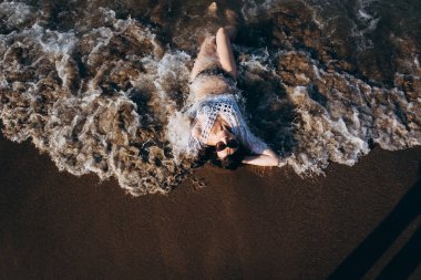 Güneş gözlüğü ve ıslak sahil üzerinde döşeme bikini içinde kadın üstten görünüm