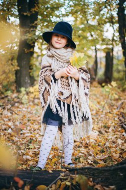 Kız panço ve şapka sonbahar ormanda yürüyüş